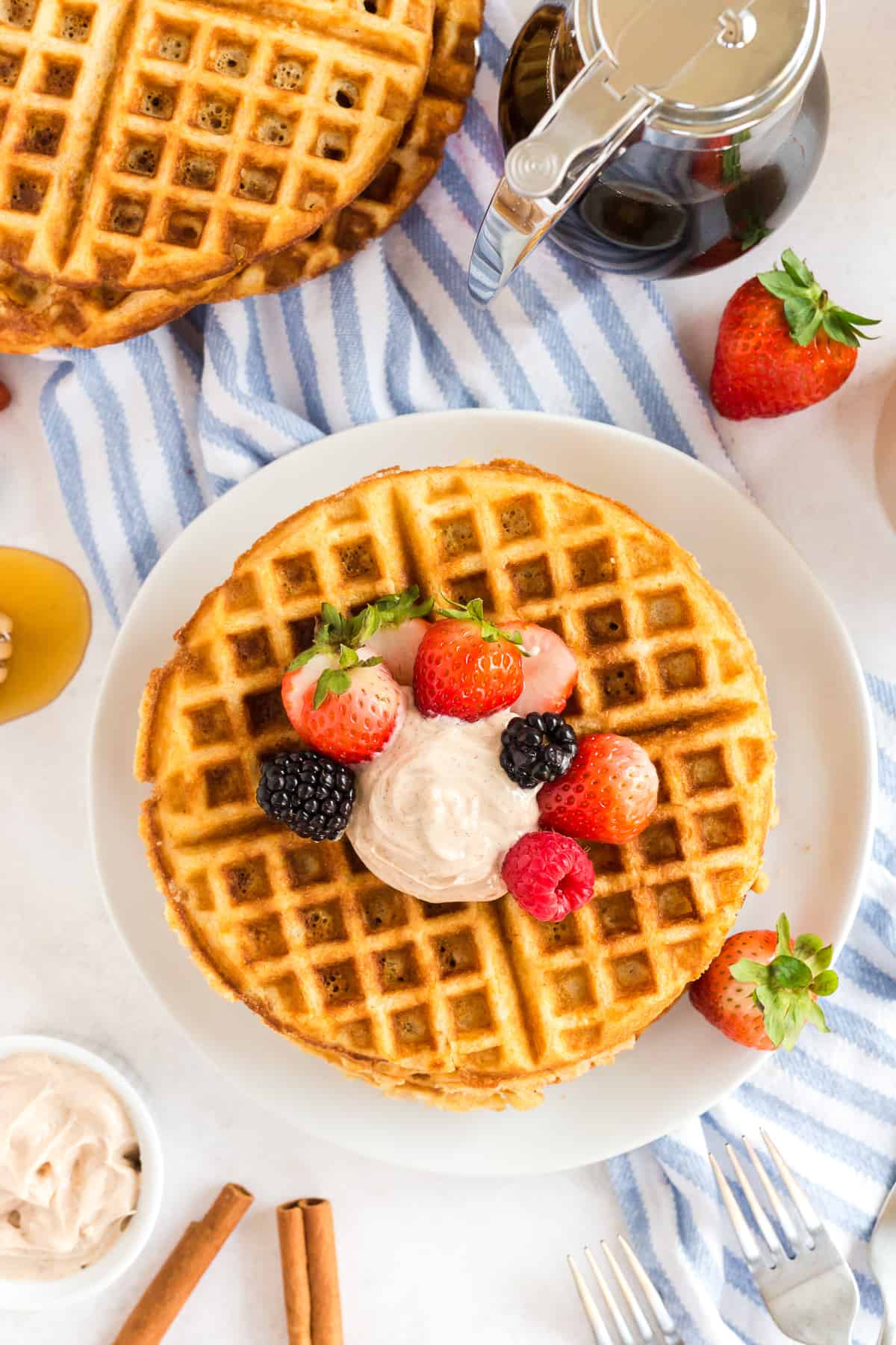 An over the top shot of cornbread waffles topped with berries and butter.