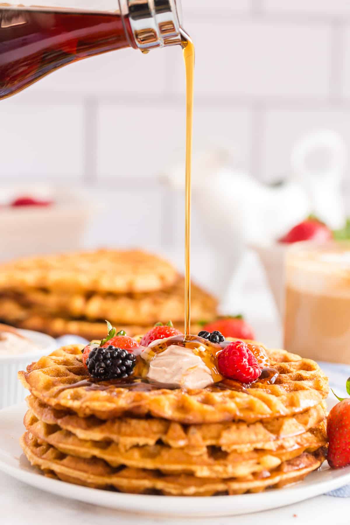 Maple syrup pouring on to a stack of sweet cornbread waffles.