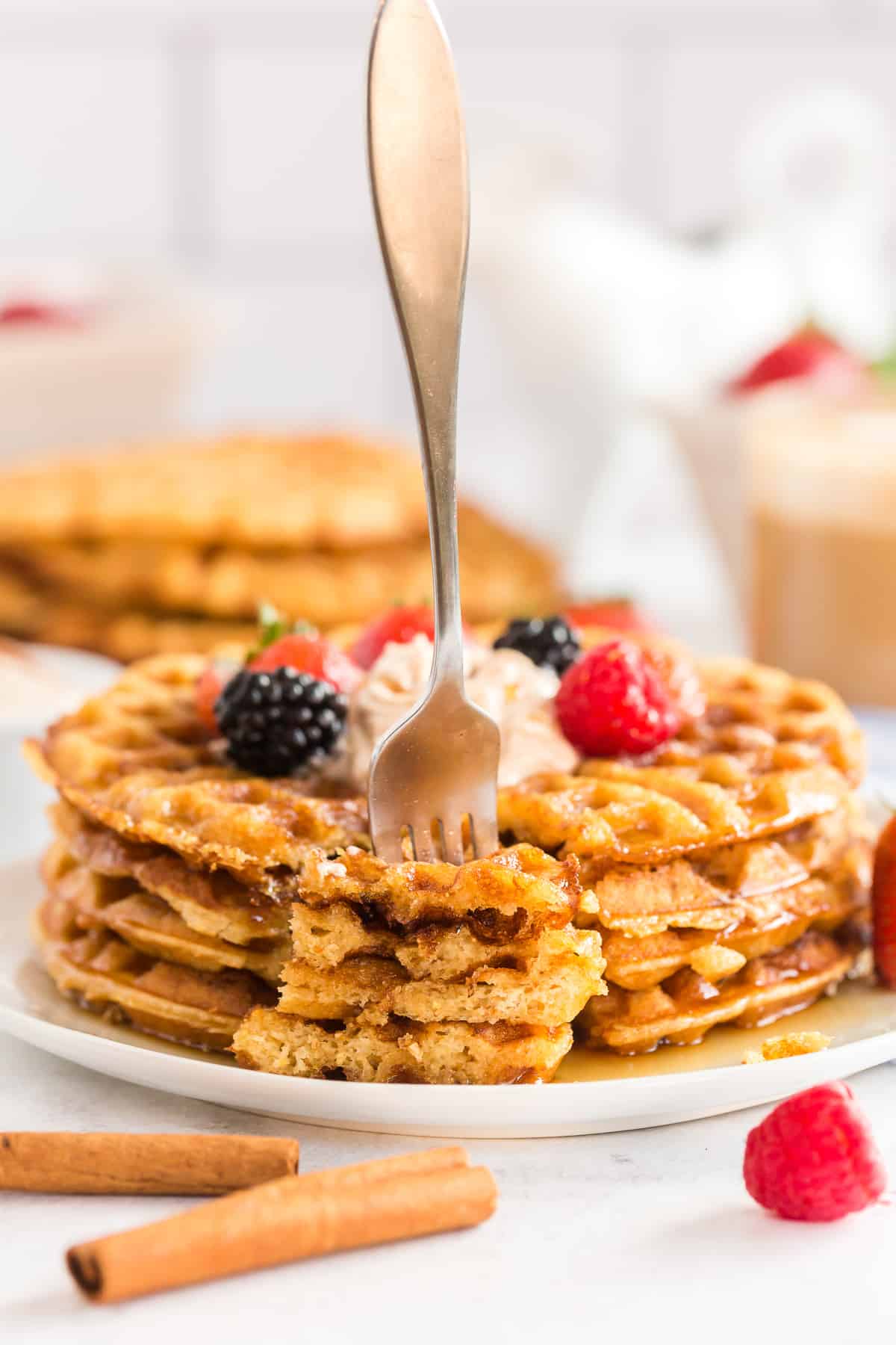 A fork stands upright stuck in pieces of sweet cornbread waffles on a plate.