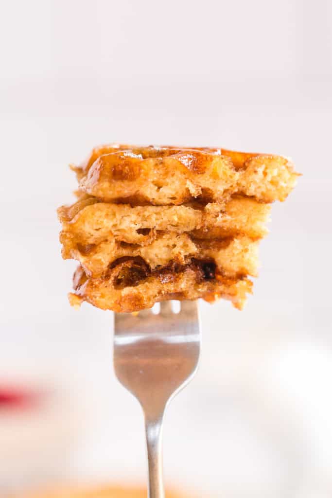 A closeup of a fork holding up pieces of waffle.