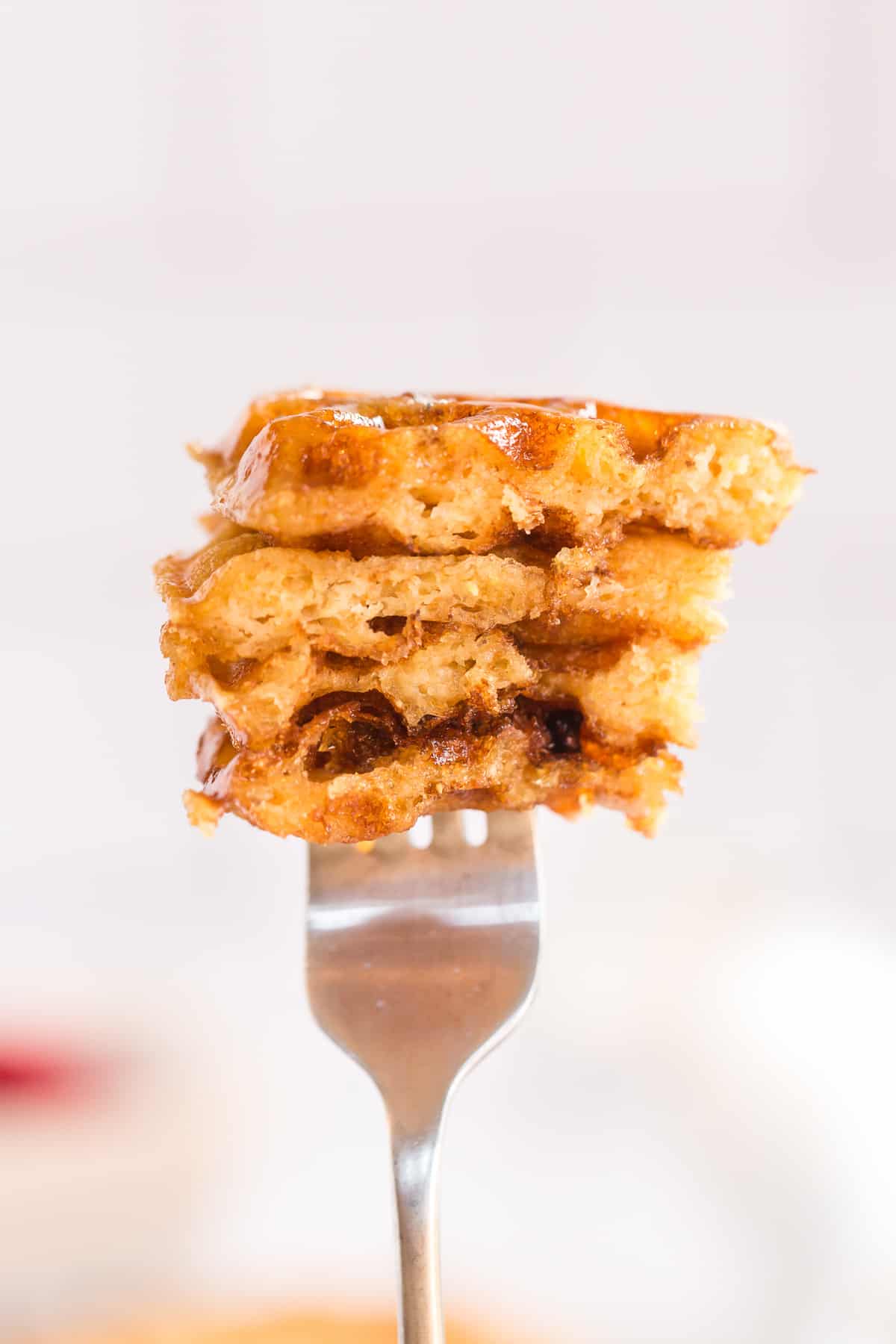 A closeup of a fork holding up pieces of waffle.