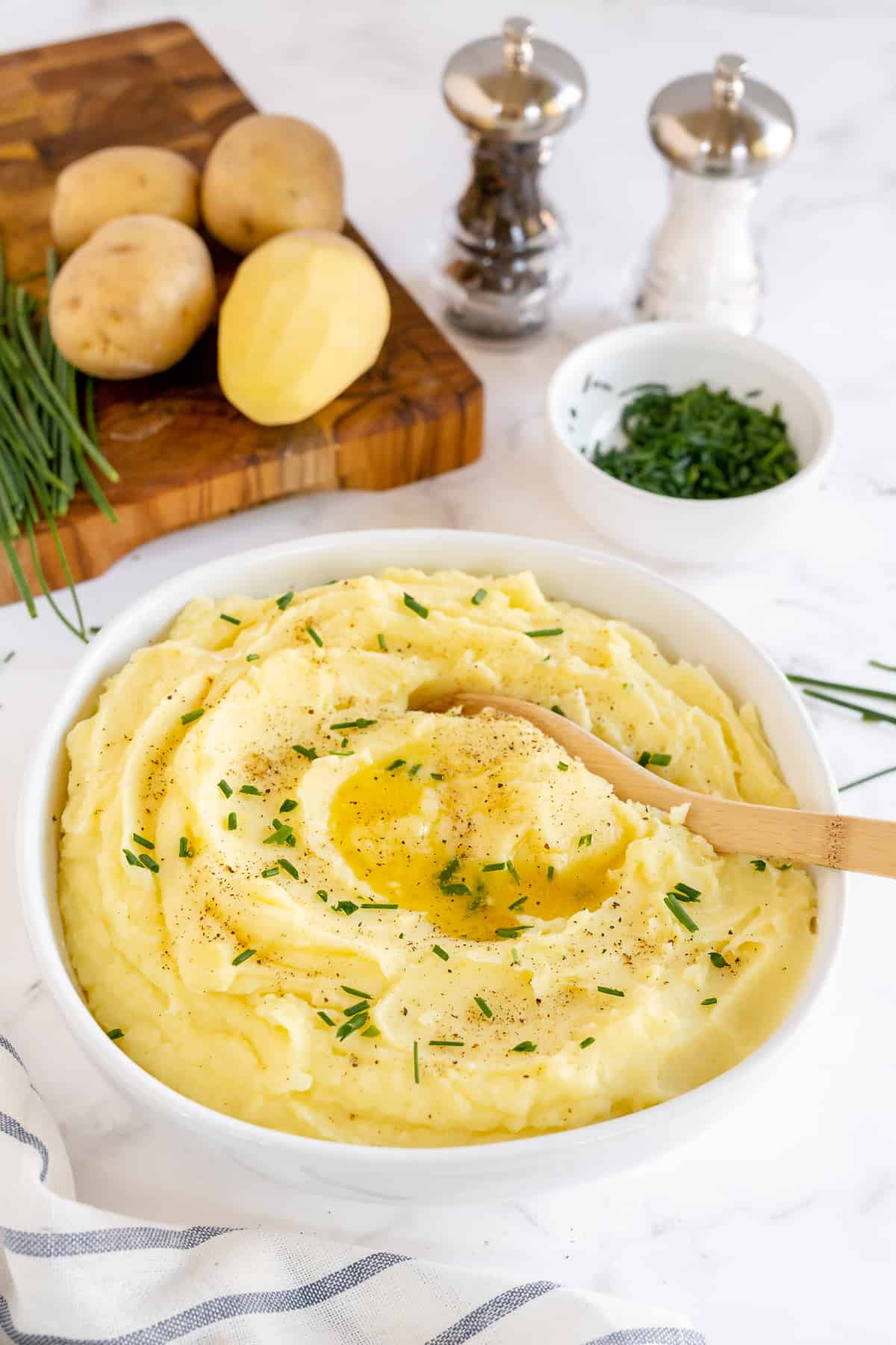 A wooden spoon in a bowl of mashed potatoes.