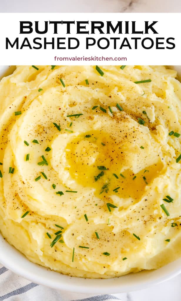 A close up of mashed potatoes swirled in a bowl with chives and butter.