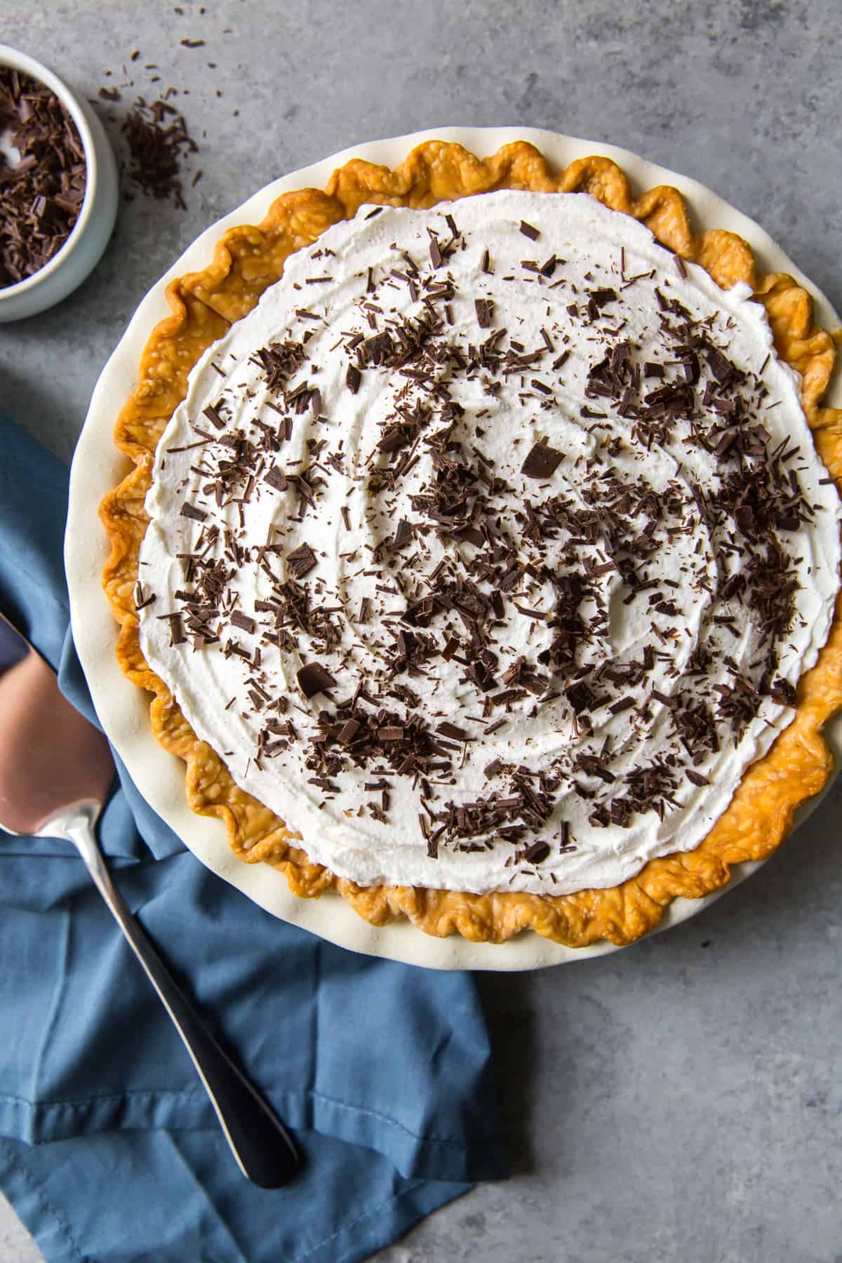 A pie topped with whipped cream and shaved chocolate shot from over the top.