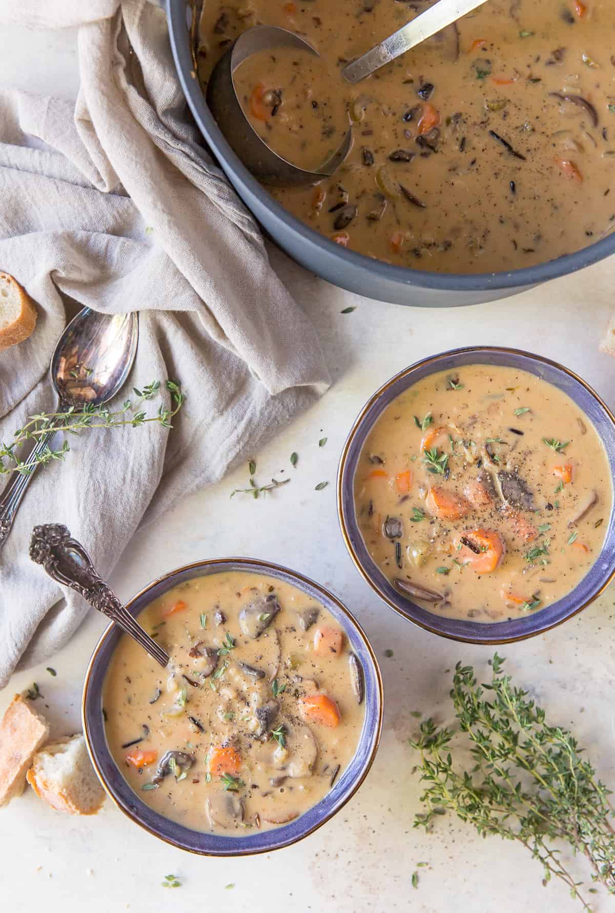 Two bowls of soup next to a soup pot with a ladle.