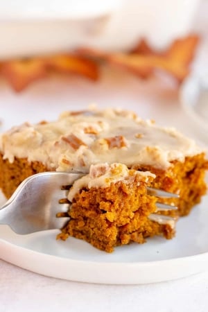 A fork breaks into a slice of pumpkin gingerbread on a plate.