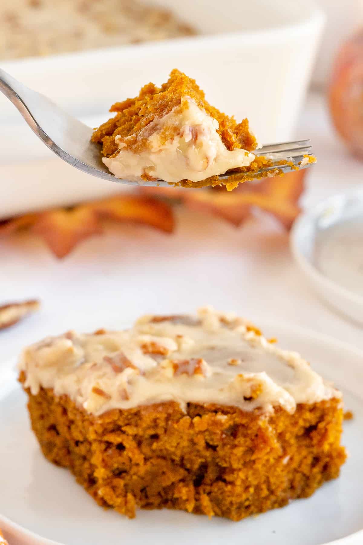 A fork lifts a bite of pumpkin gingerbread from a plate.