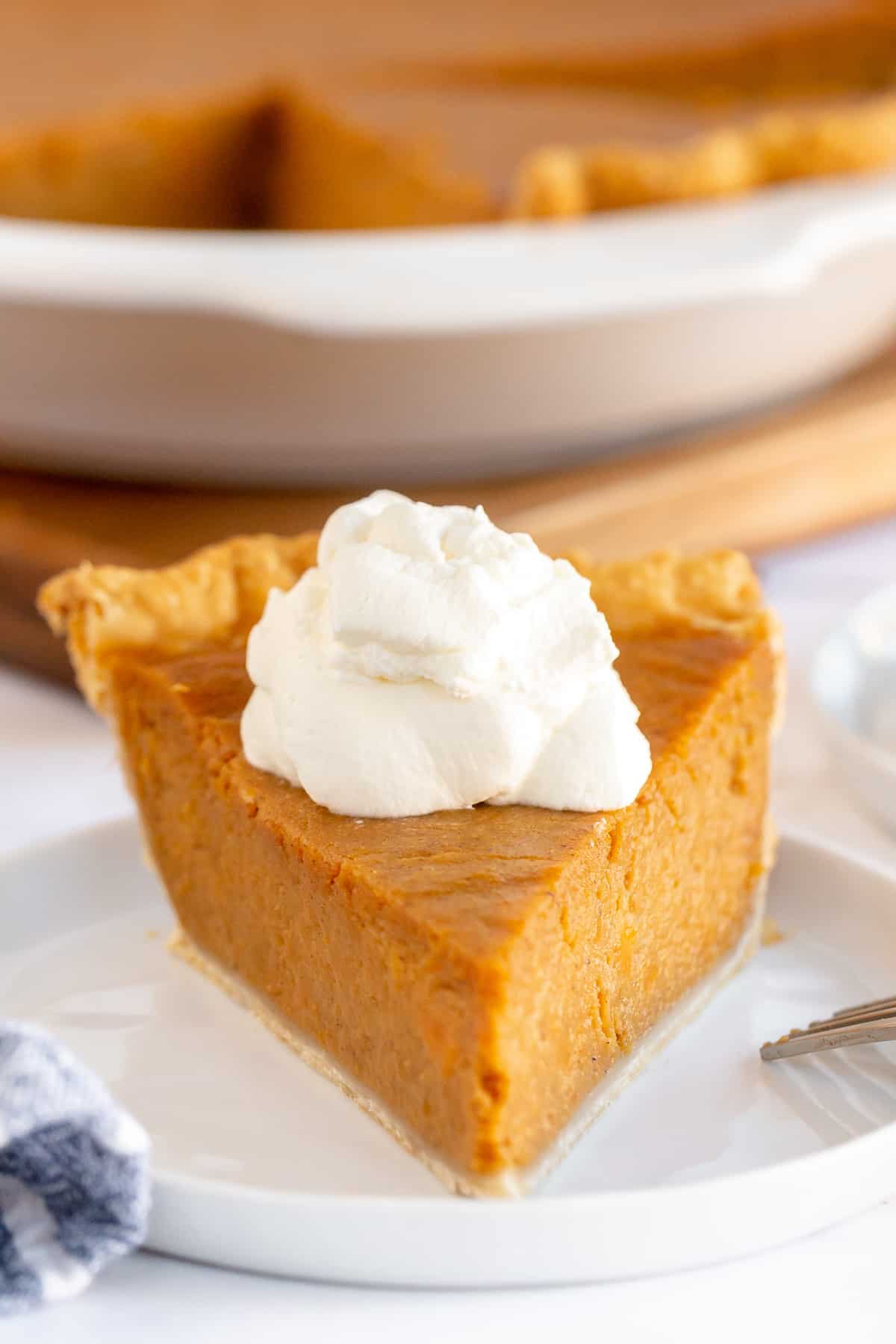 A slice of sweet potato pie toped with whipped cream.