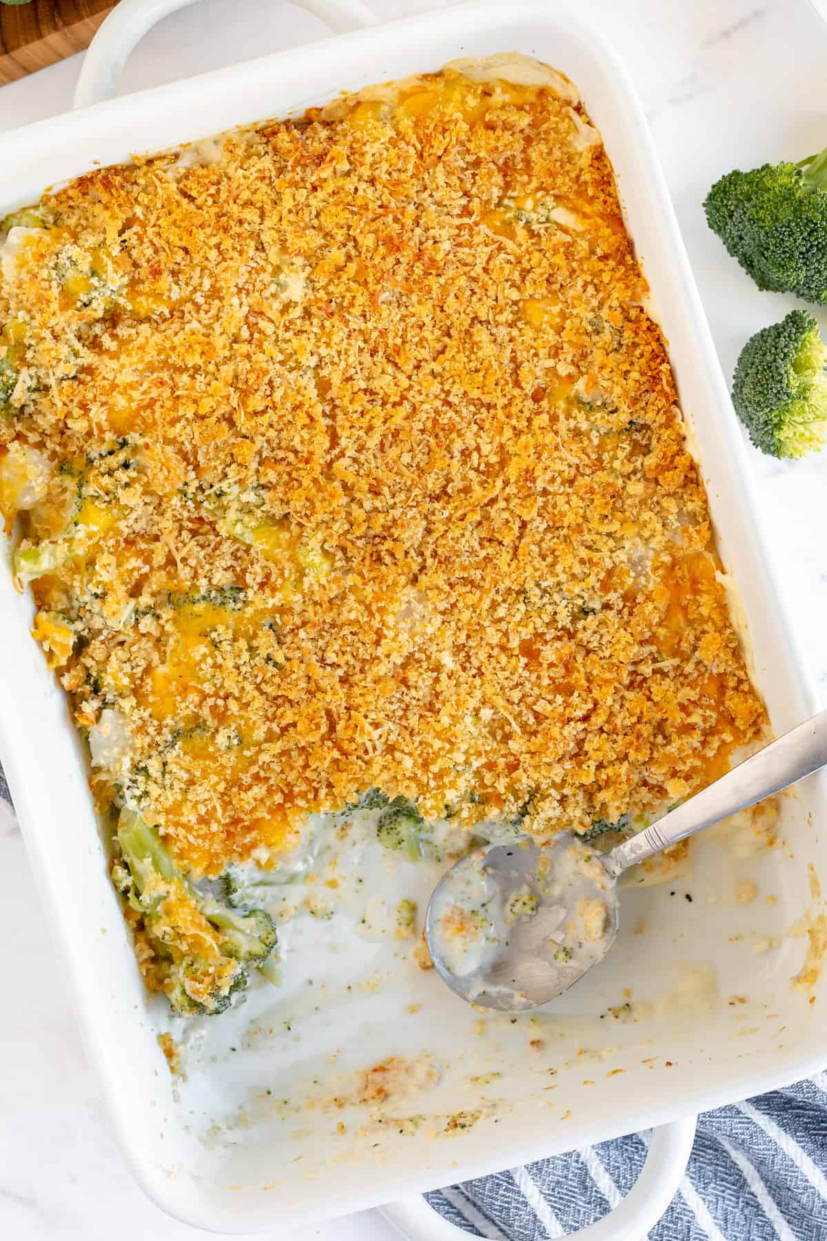 An over the top shot of a Broccoli Pearl Onion Casserole with a spoon resting in the baking dish.