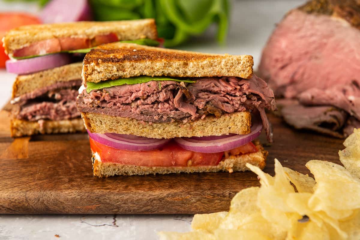 Half of a roast beef sandwich on a cutting board.