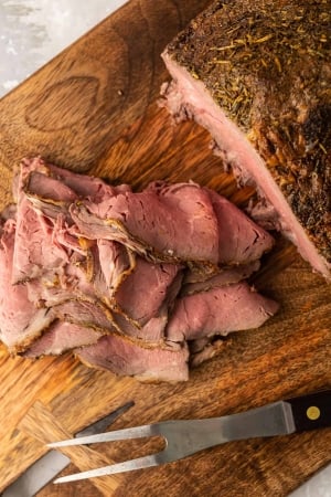 A pile of thinly sliced roast beef on a cutting board.