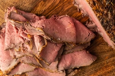 A pile of thinly sliced roast beef on a cutting board.