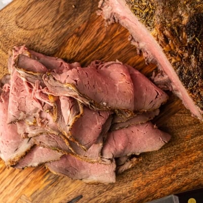 A pile of thinly sliced roast beef on a cutting board.