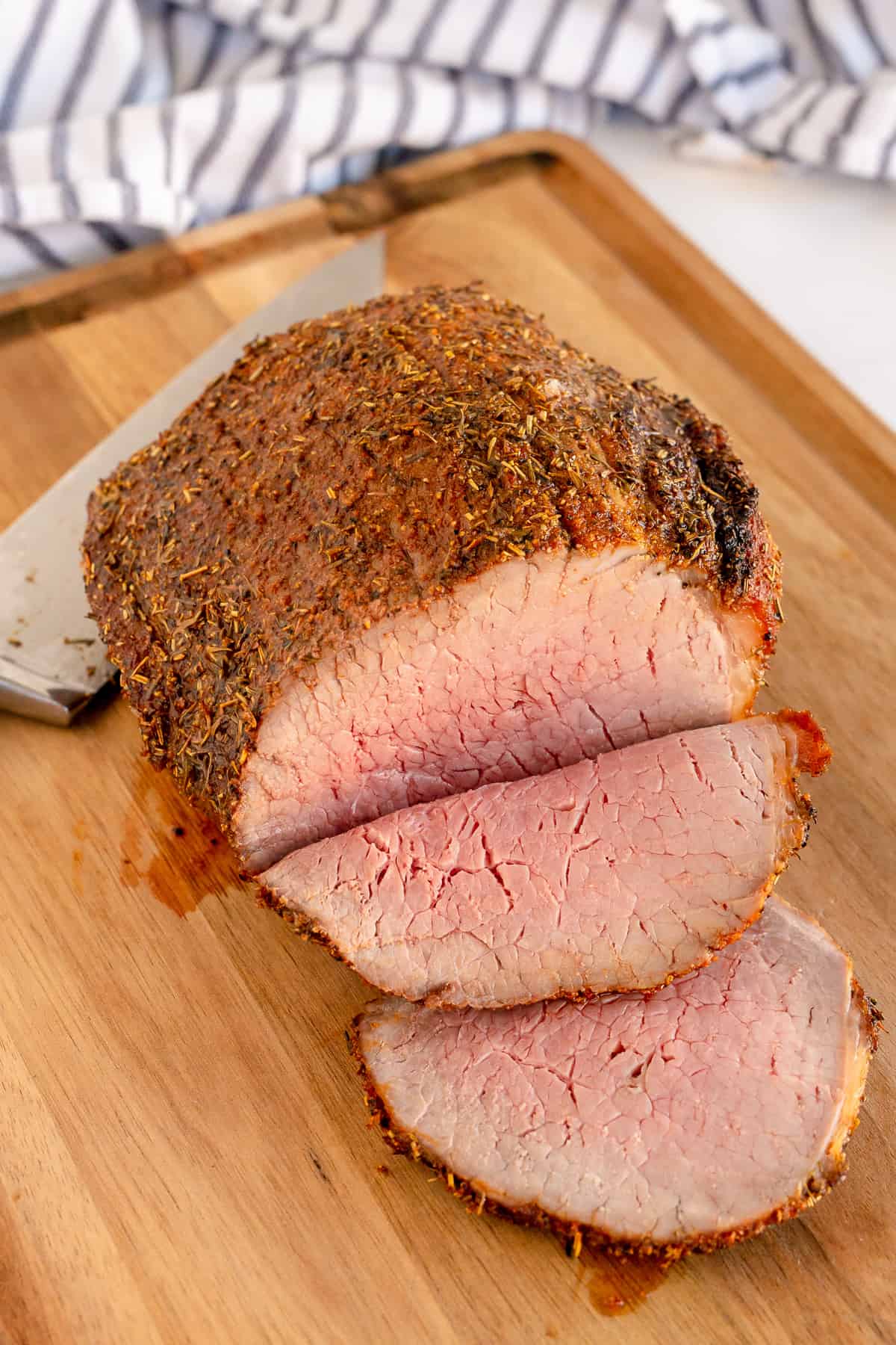 Sliced eye of round roast beef on a cutting board.