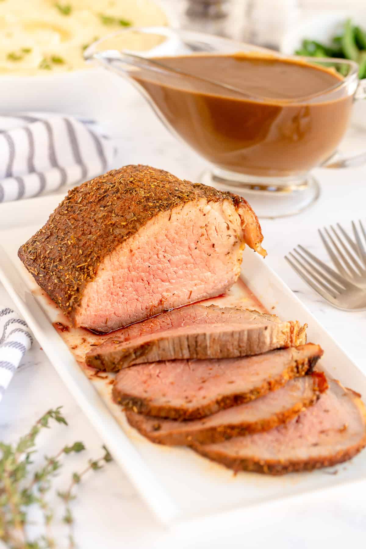 Juicy sliced roast beef on a white platter.