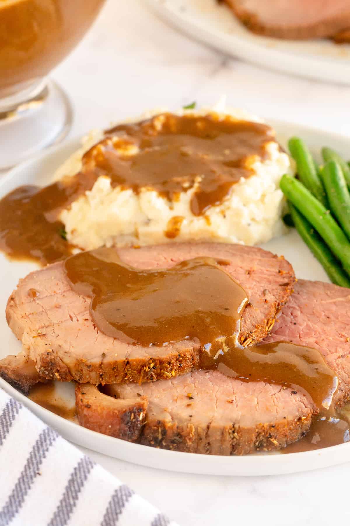 Slices of roast beef with gravy and mashed potatoes on a plate.