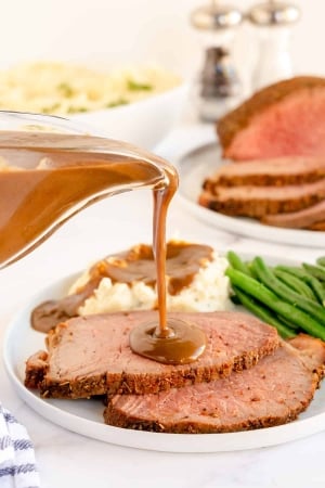 Gravy pours on to slices of roast beef.
