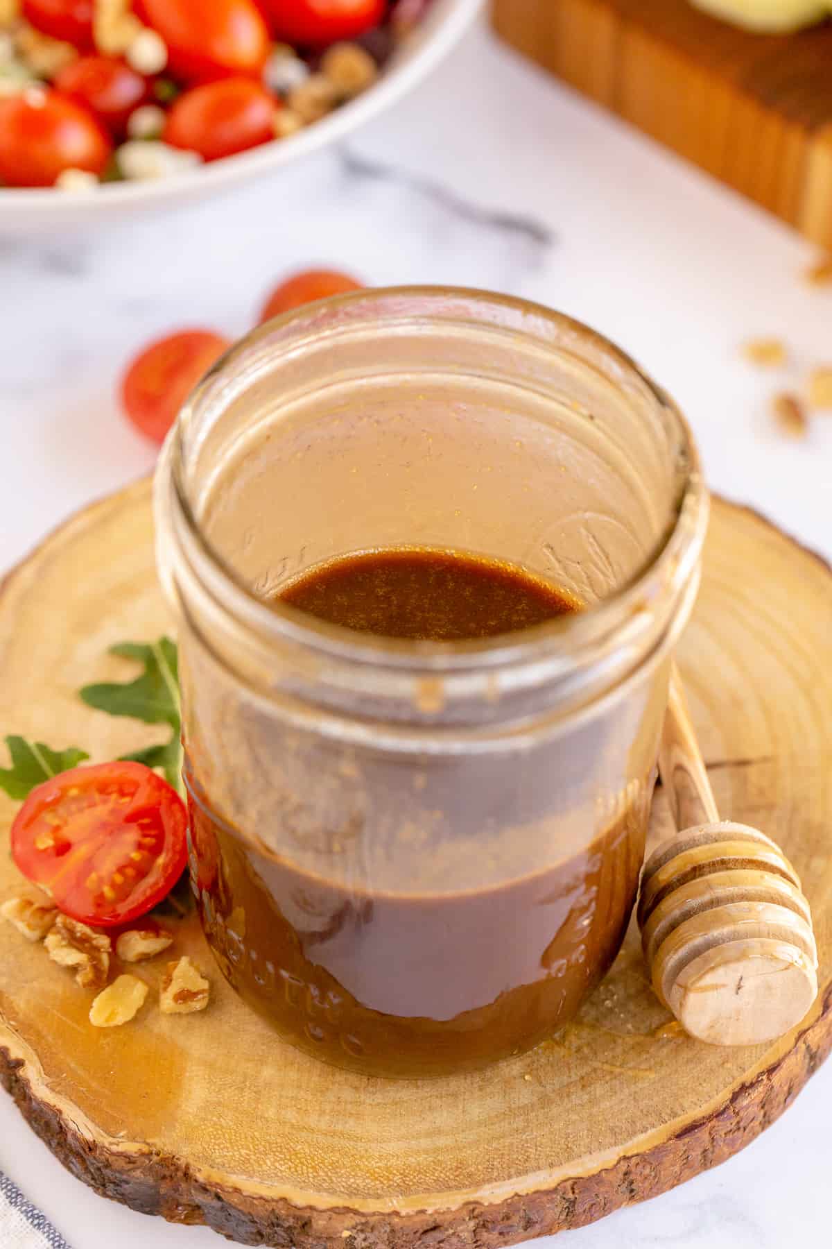 An open mason jar filled with honey balsamic salad dressing .