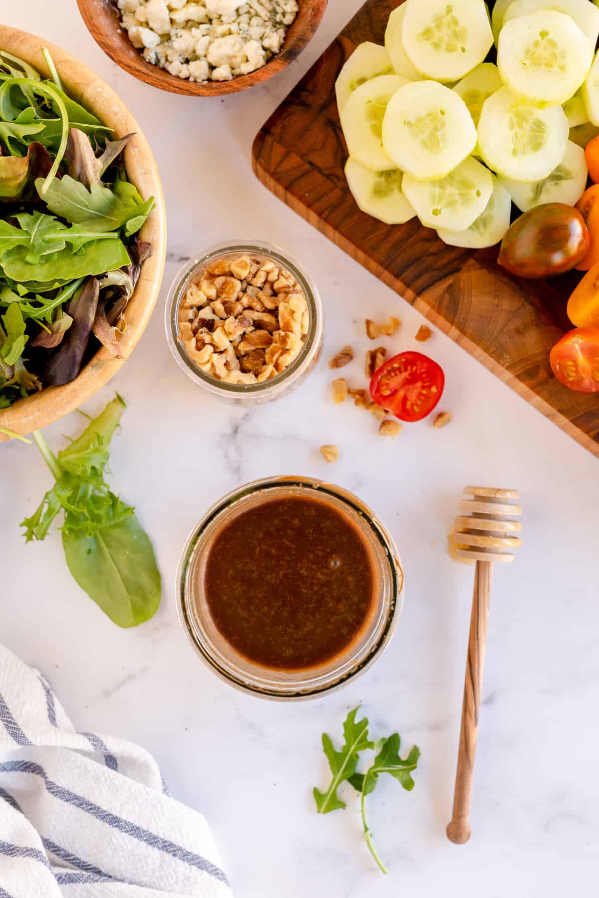 A jar of vinaigrette surrounded by salad ingredients.