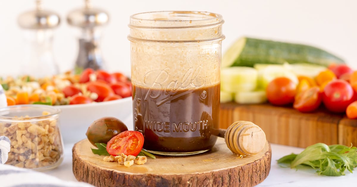 Honey Balsamic Vinaigrette in a mason jar with vegetables around it.