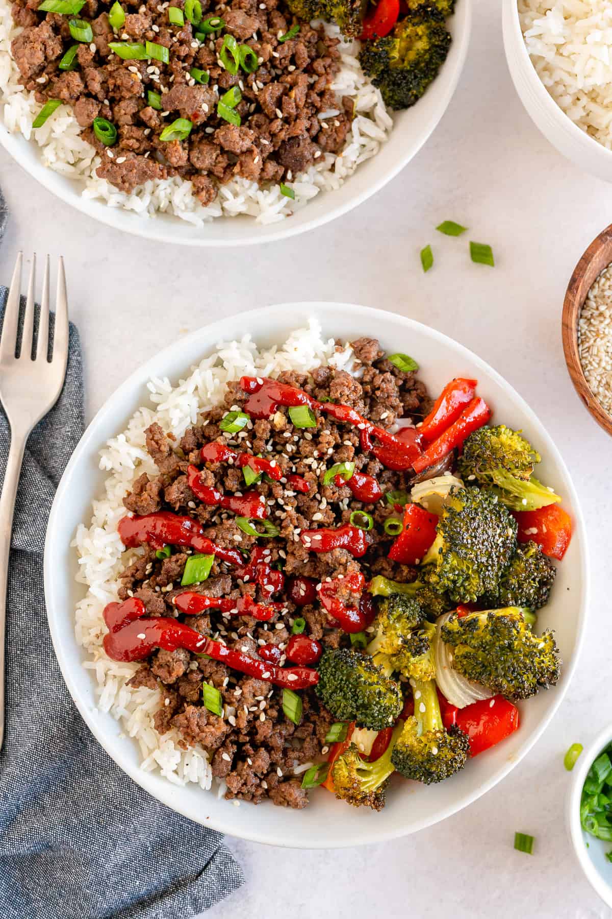 Korean Ground Beef topped with Go Chu Jang sauce in a white bowl with vegetables.