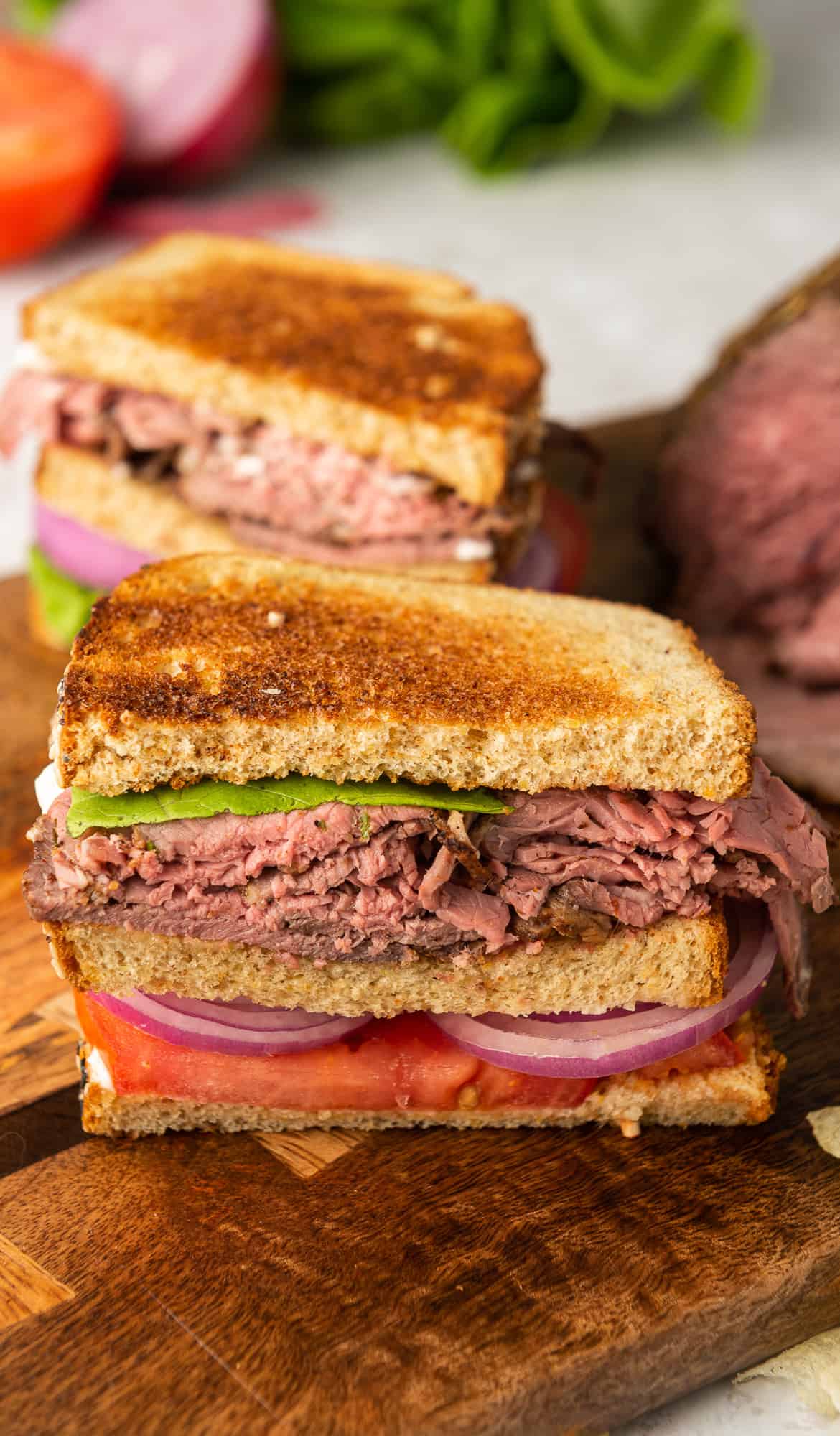 A close up of half of a roast beef sandwich on a cutting board.