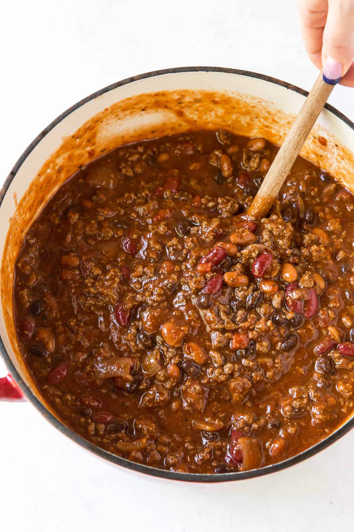 A wooden spoon stirs a pot of Halftime Chili.