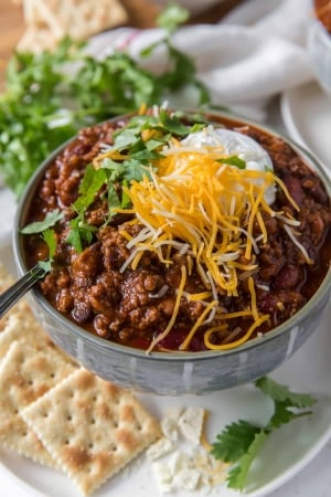 A bowl of chili topped with cheese and sour cream.