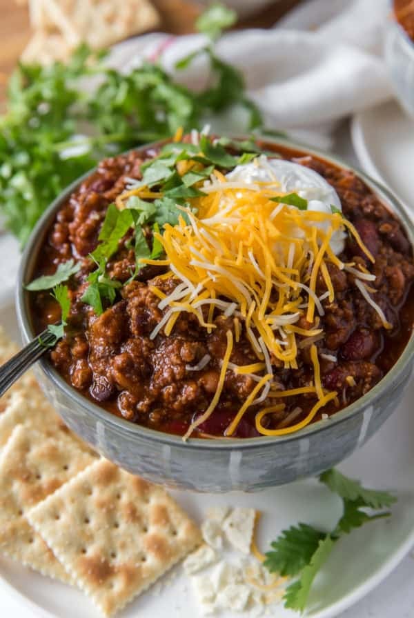 A bowl of chili topped with cheese and sour cream.