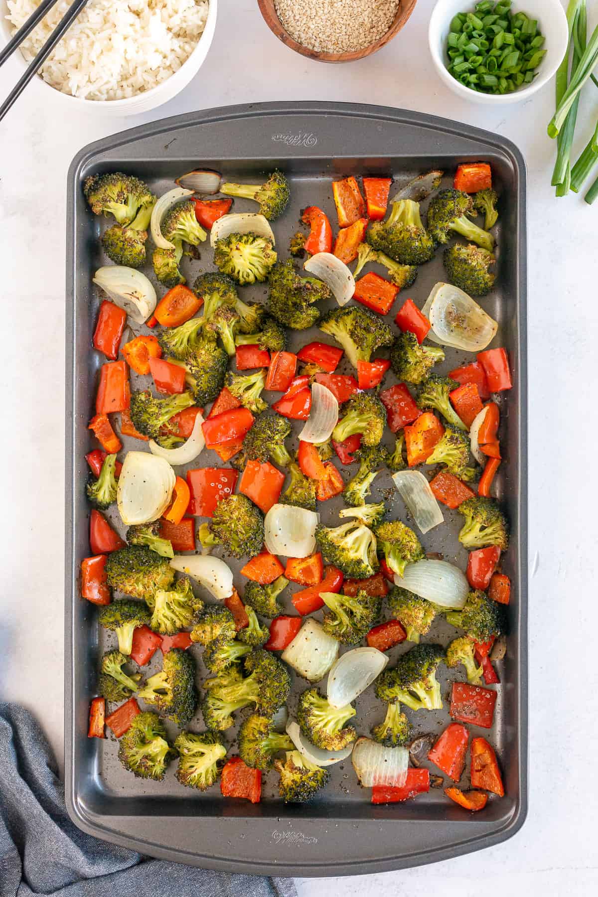 Broccoli, onion and red bell pepper on a baking sheet.