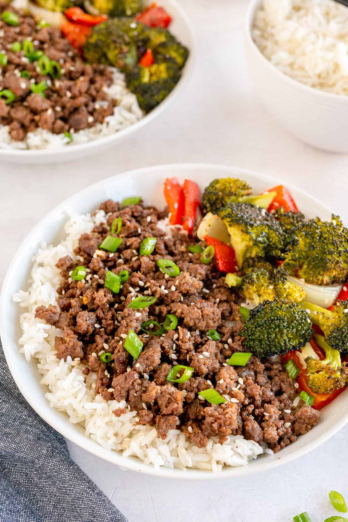 Korean beef o top of rice with vegetables in a white bowl.