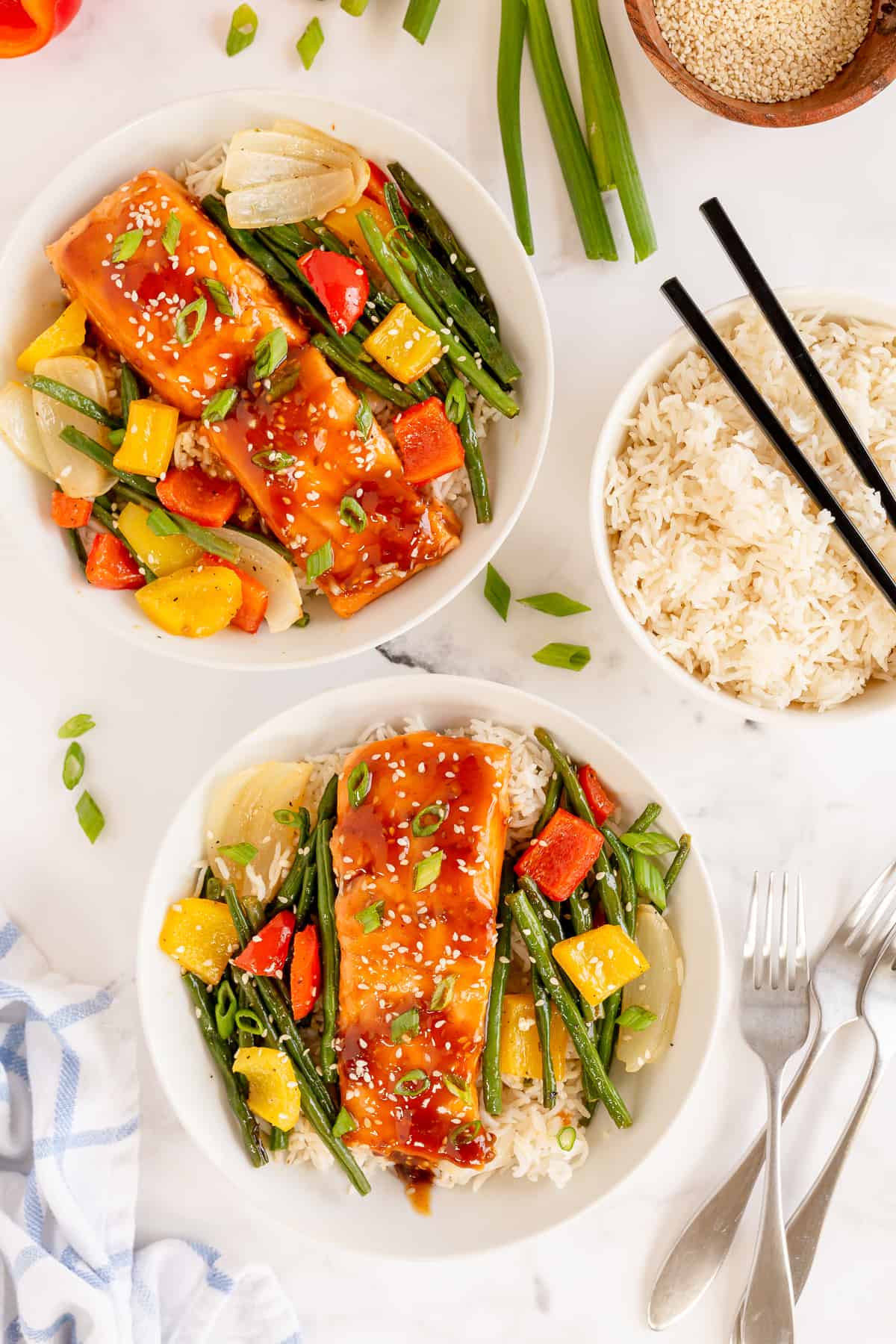Two bowls filled with vegetables and salmon teriyaki on rice.