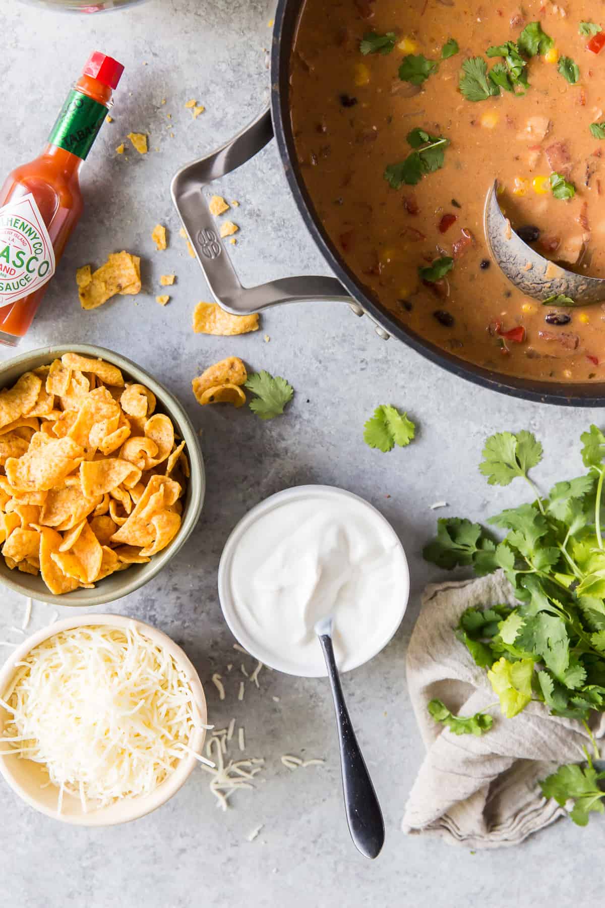 A big pot of soup next to topping ingredients.