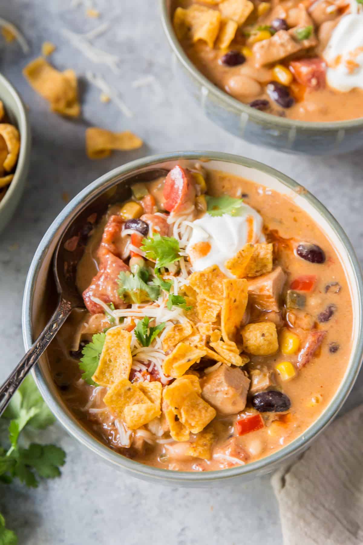 A spoon in a bowl of soup with chicken and black beans.