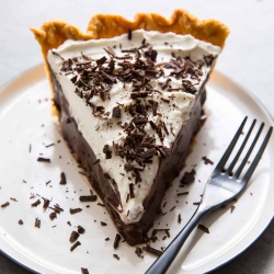 A close up of a slice of pie on a white plate with a fork.