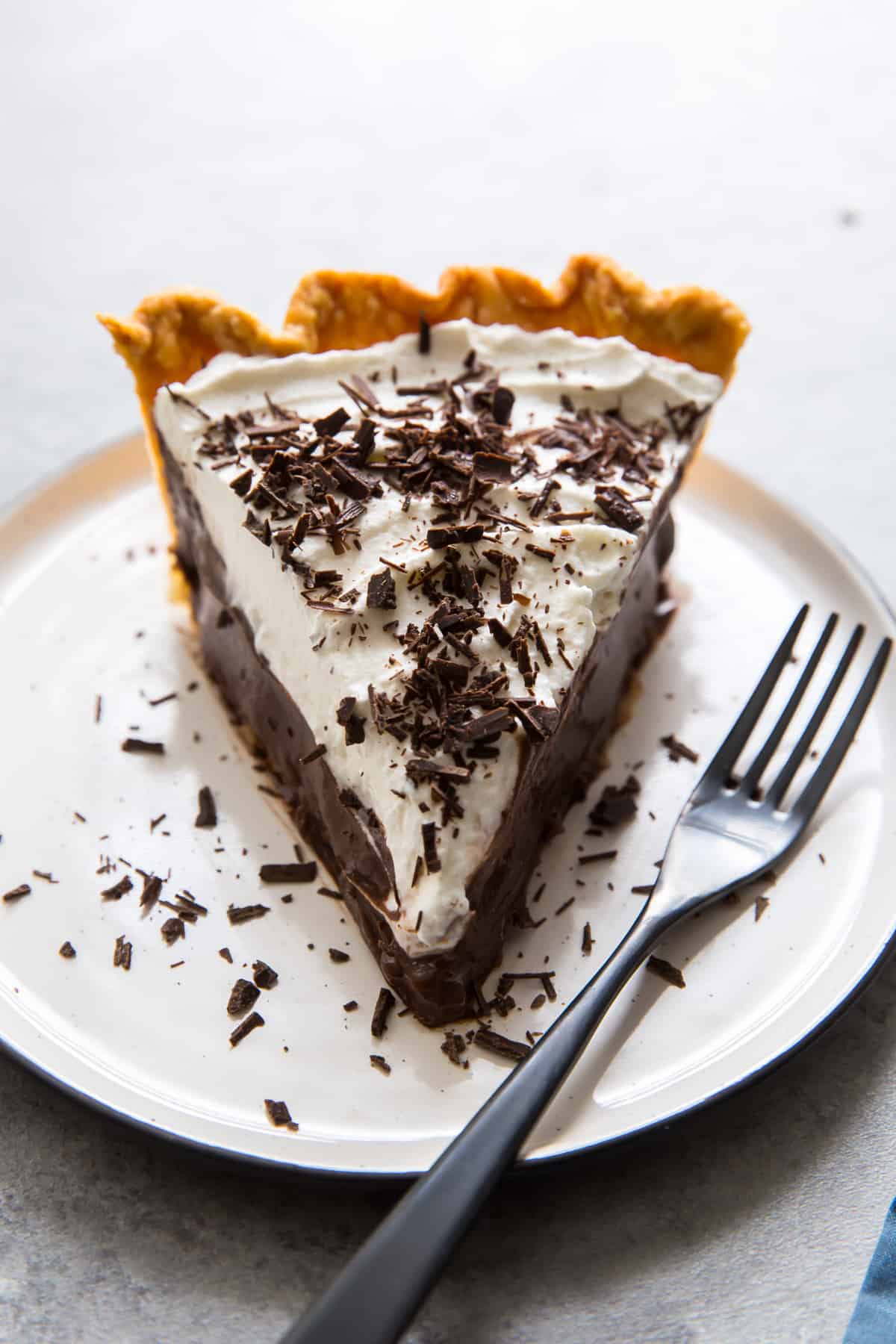 A close up of a slice of pie on a white plate with a fork.