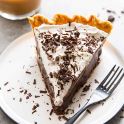A slice of chocolate pie on a white plate with a fork.