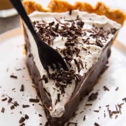 A fork breaks into a slice of chocolate cream pie.