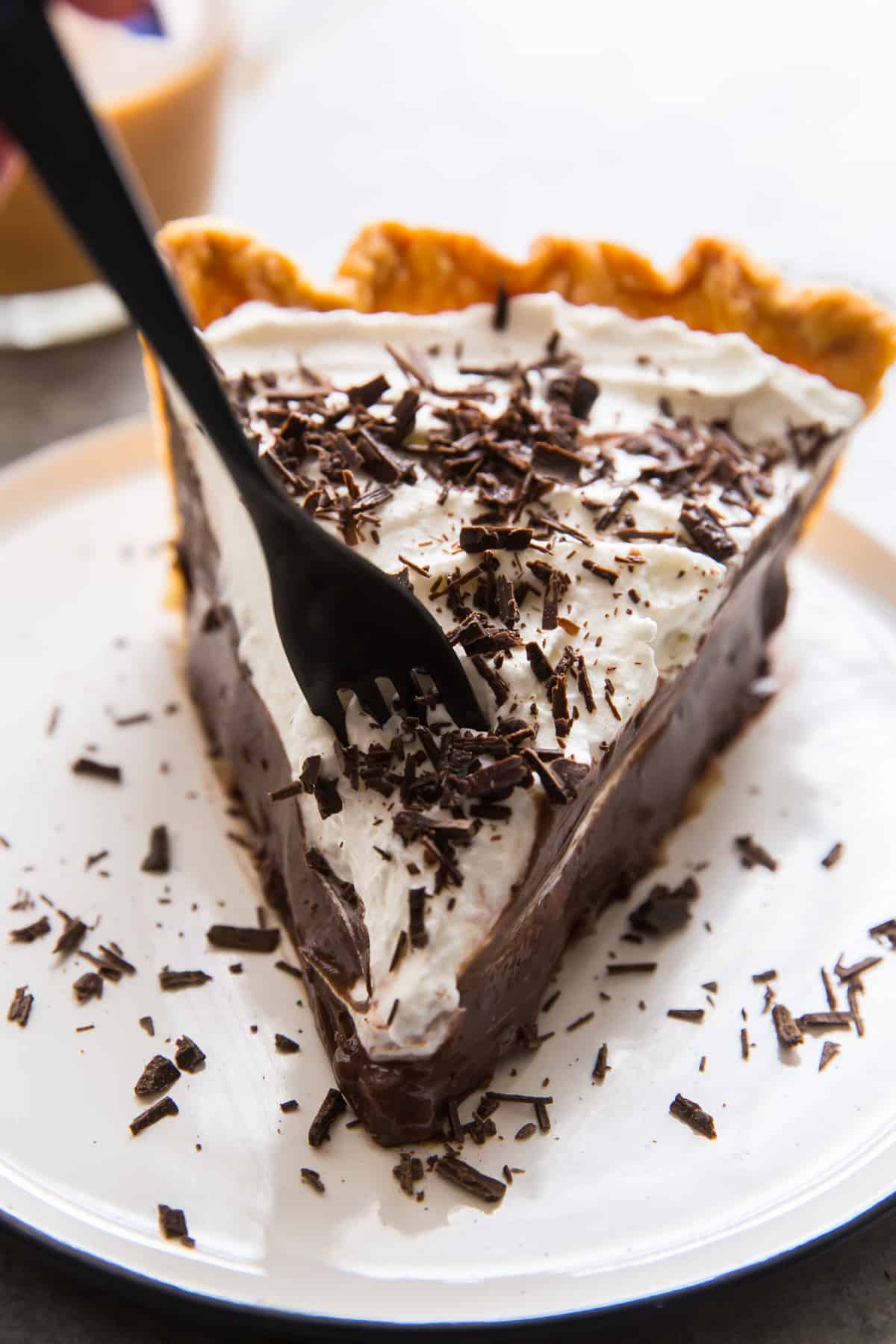 A fork breaks into a slice of chocolate cream pie.