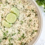 Skillet filled with fluffy Cilantro Lime Rice garnished with fresh cilantro and lime slices.