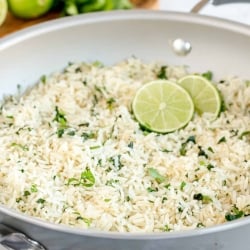 A skillet filled with white rice, cilantro and lime slices.