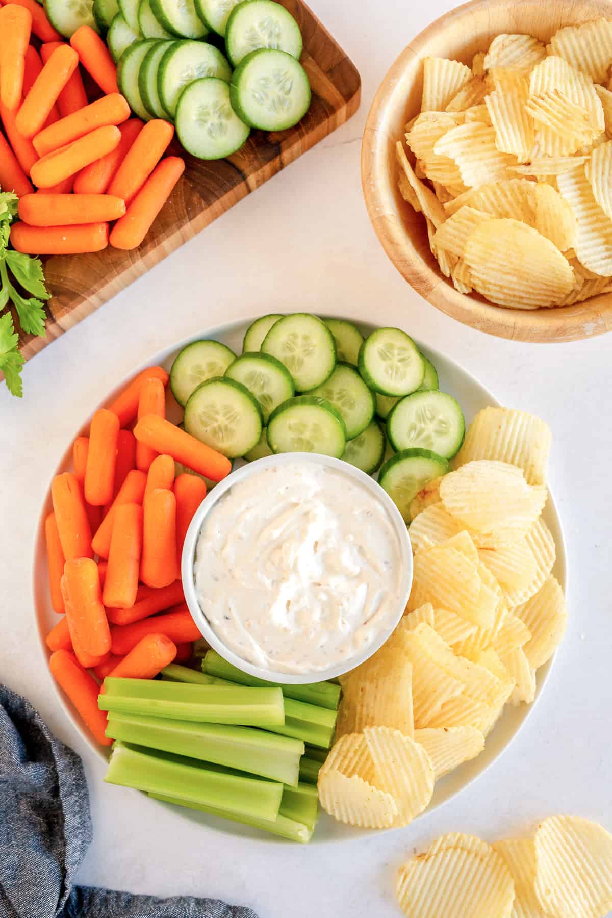 A platter of vegetables and Ruffles chips with dip in the center.