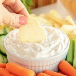 A chip being dipped into a small dish of French onion dip.