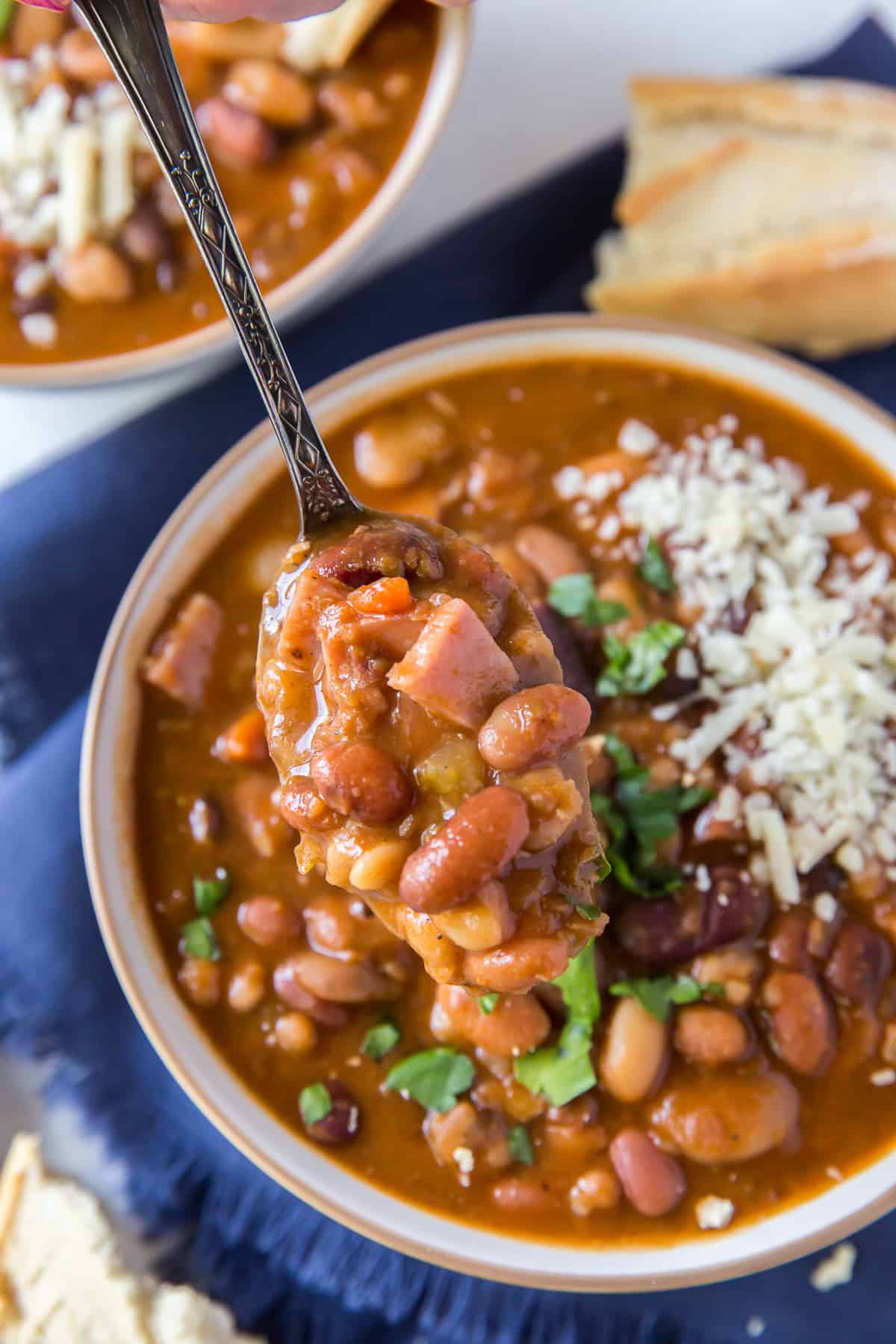 A hand lifts a spoonful of soup from a bowl.