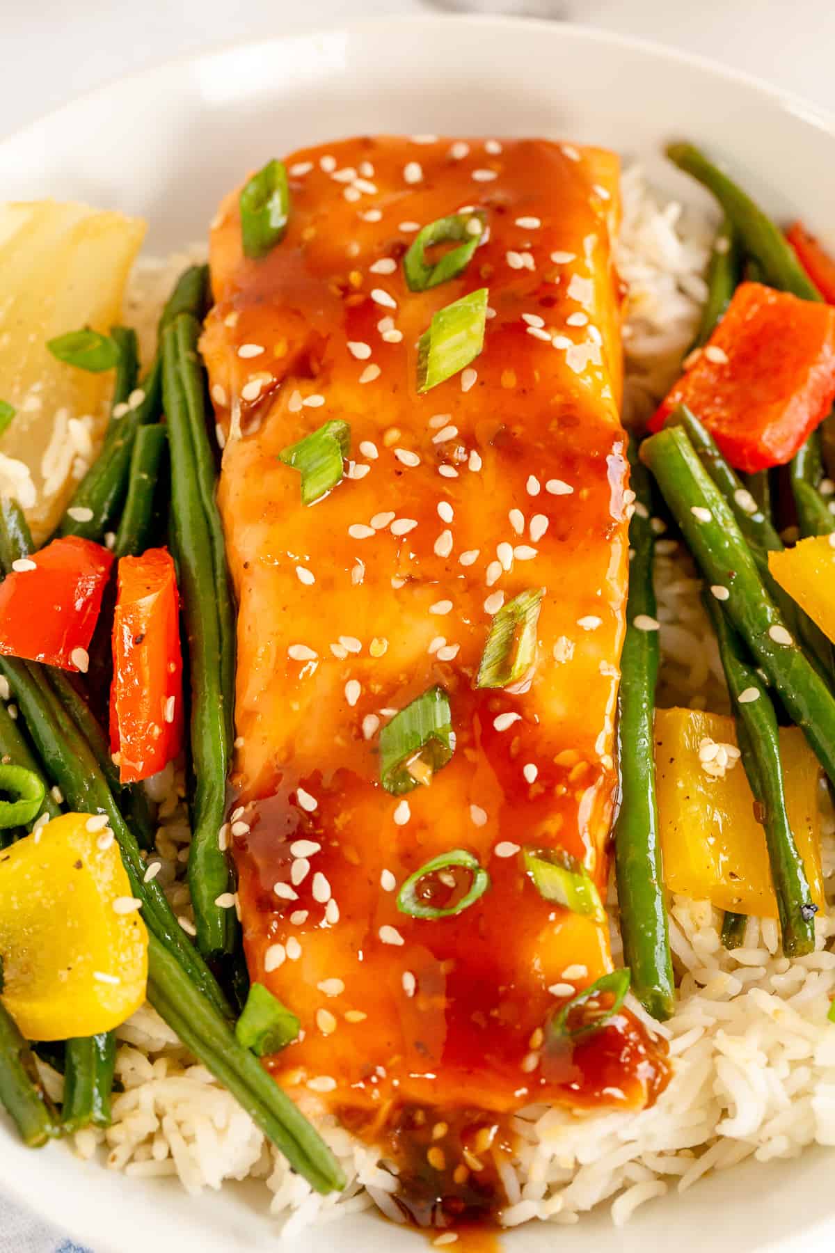 A close up of salmon teriyaki in a bowl with rice and veggies.