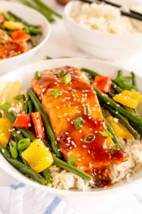 Salmon and vegetables on top of rice in a bowl.