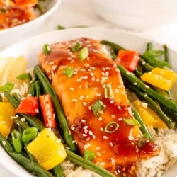 Salmon and vegetables on top of rice in a bowl.