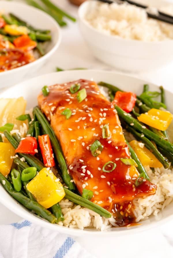 Salmon and vegetables on top of rice in a bowl.