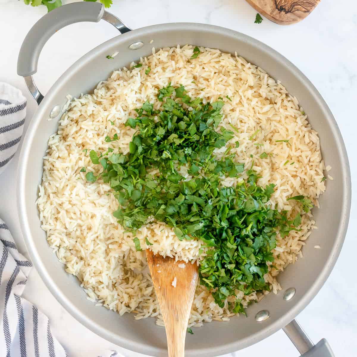 Adding chopped cilantro to cooked rice for homemade cilantro lime rice.