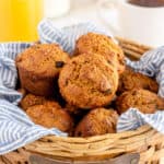 A basket lined with a blue cloth and filled with bran muffins.